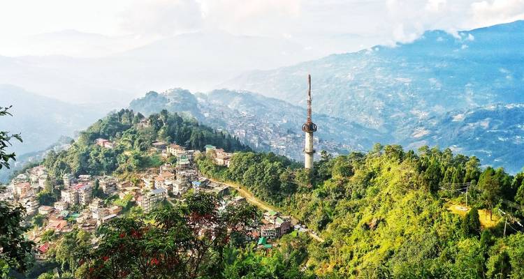 Panoramic hill-top view over Gangtok city and surrounding green ridges fading into misty Himalayan ranges