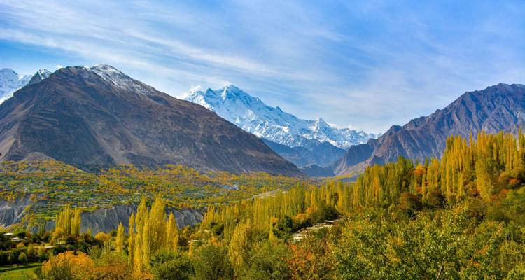 Une vue panoramique des pics enneigés se dressant au-dessus de la vallée fertile de Hunza aux couleurs automnales.