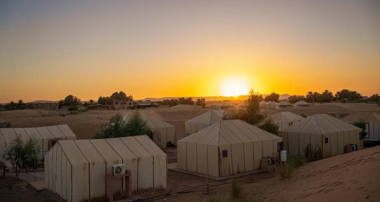 Filas de tiendas de campamento del desierto bajo un amanecer brillante en el Sahara cerca de Merzouga.