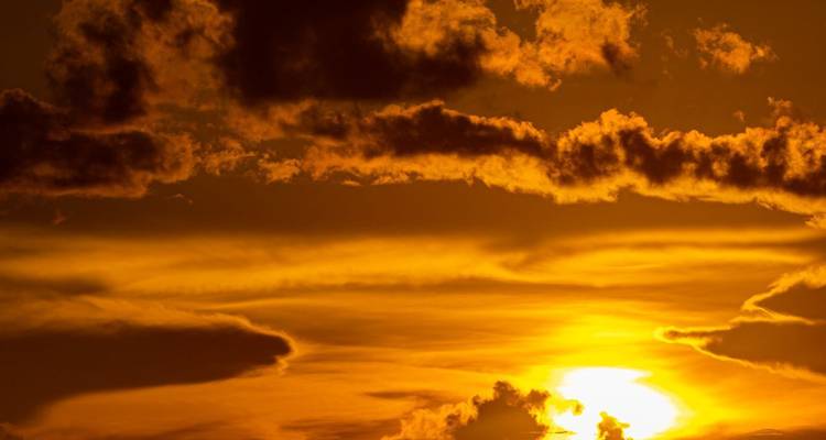 Ciel de coucher de soleil orange et doré dramatique avec des nuages superposés.