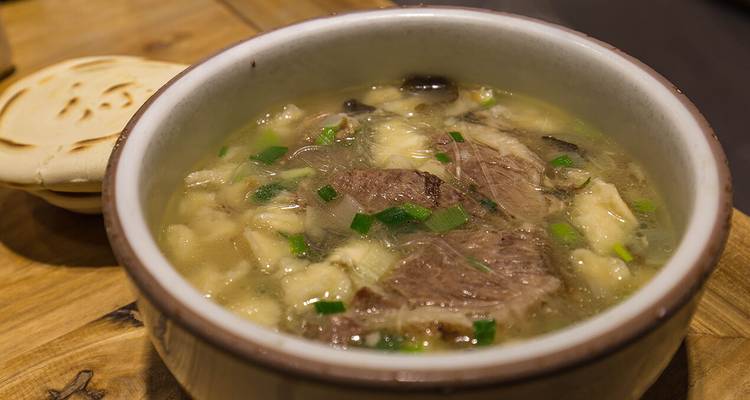Hearty bowl of Yangrou Paomo mutton soup with diced bread soaking in rich broth.
