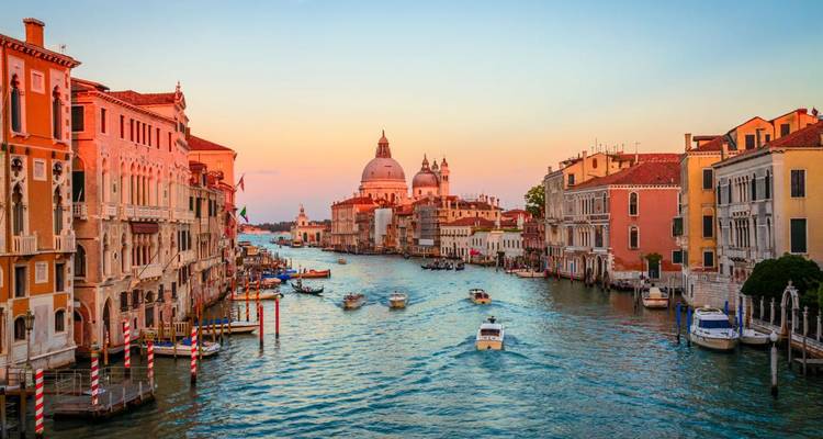 Iconische Grand Canal van Venetië met boten die bij zonsondergang naar Santa Maria della Salute glijden.