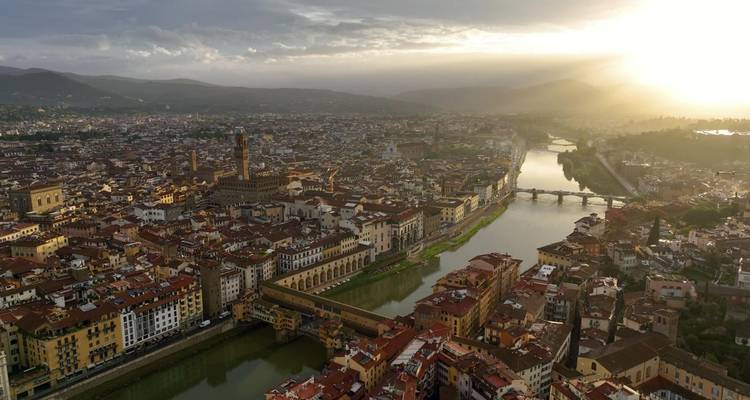 Luchtfoto van Florence met de Arno rivier en de Ponte Vecchio die gloeien in het late middaglicht.