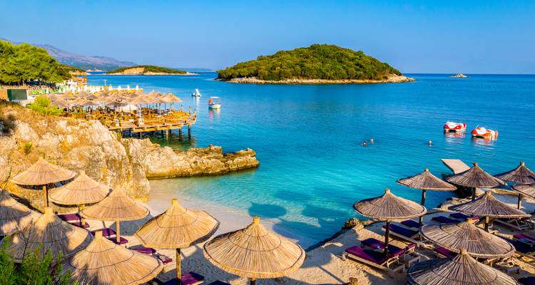 Les parasols et les chaises longues surplombent une baie turquoise spectaculaire dotée de formations rocheuses et de petites îles.