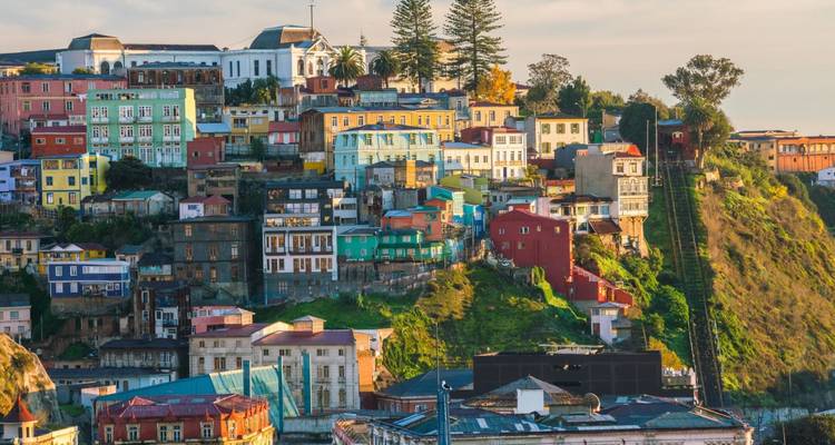 Vibrant hillside city with pastel buildings stacked above a funicular track at sunset