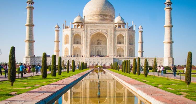 Ikonische Frontalansicht des Taj Mahal, das sich in seinem langen Wasserbecken an einem klaren, blauen Tag spiegelt.