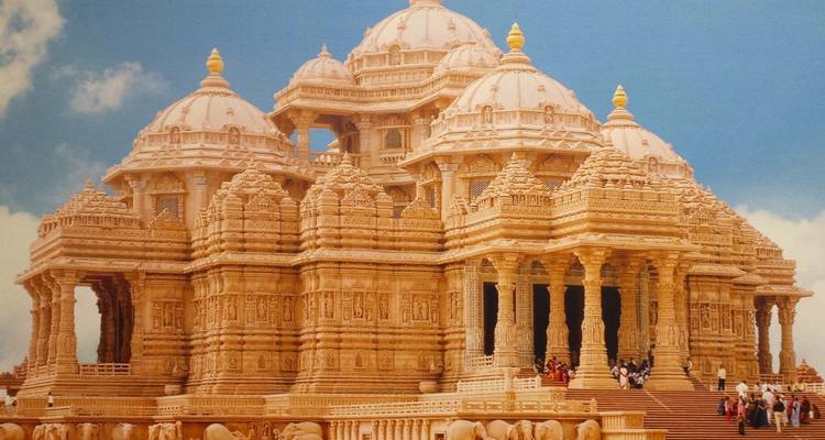 Kunstvoll gemeißelter Akshardham-Tempel aus Sandstein vor einem leuchtend blauen Himmel.