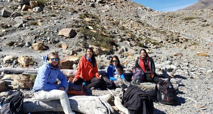 Small group rests on rocky terrain during a Patagonian trek with backpacks nearby.