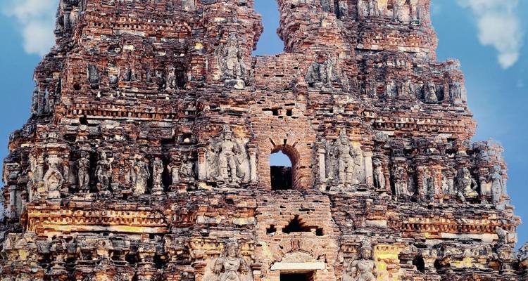 Nahaufnahme von kunstvollen Sandsteinskulpturen an einem antiken indischen Tempel-Gopura vor blauem Himmel.
