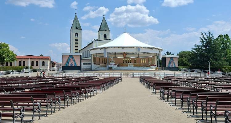 Filas de bancos vacíos conducen hacia el altar al aire libre y las dos torres de la Iglesia de Santiago en Medjugorje.