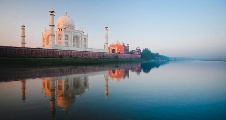 Das Taj Mahal leuchtet in sanftem Glanz bei Sonnenaufgang, sein Spiegelbild spiegelt sich vollkommen im Yamuna-Fluss wider.