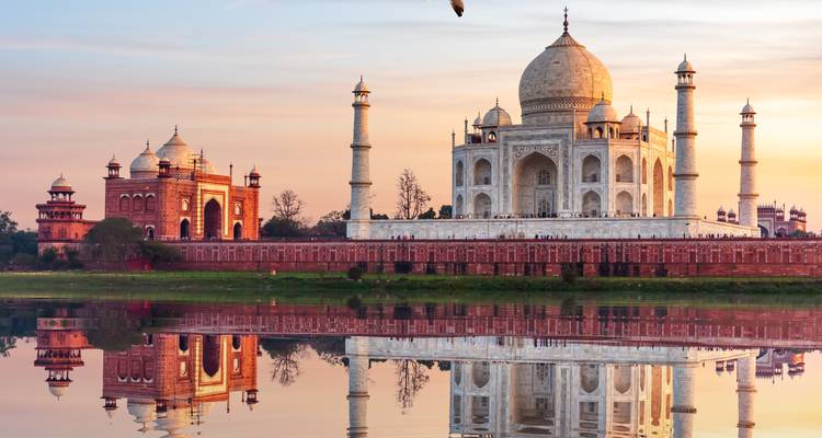 Das Taj Mahal und die Moschee spiegeln sich perfekt im Yamuna-Fluss bei zartem Sonnenuntergangslicht wider.