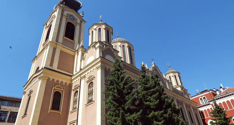 Ornate Orthodox cathedral with multiple domes and bell tower against a deep blue sky.