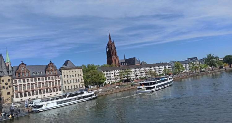 Rivierfront uitzicht van Frankfurt met kathedraalspits en rondvaarttochten op de Main.
