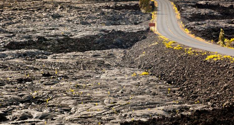 Eenzame asfaltweg die zich door enorme velden van verharde lava slingert in Hawaii Volcanoes National Park.