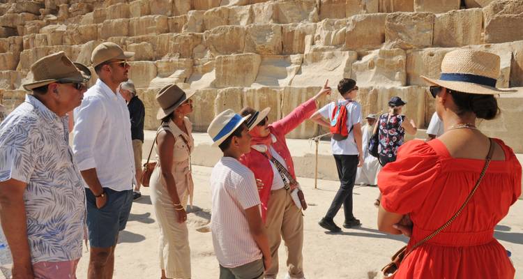 Un guide explique les pierres de la pyramide à un groupe de touristes attentif.