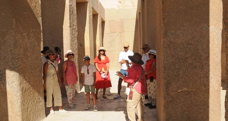 Un groupe de touristes écoute un guide dans un couloir bordé de granit près de Giza.