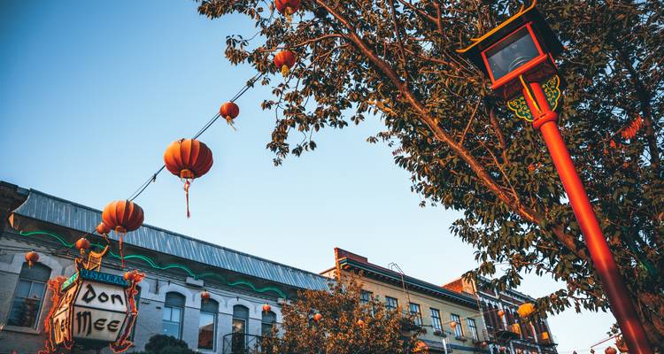 Vue ascendante de lanternes rouges et de bâtiments patrimoniaux de Chinatown contre un ciel bleu limpide en soirée.
