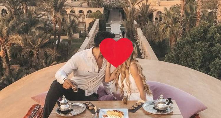 Couple savourant un petit-déjeuner sur le toit avec des services à thé marocains et un graphique en forme de cœur masquant les visages.
