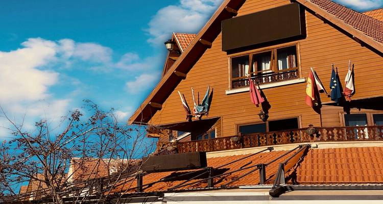 Bâtiment de style alpin en bois avec de petits drapeaux sous un ciel bleu dégagé.