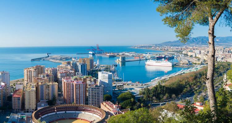 Erhöhter Aussichtspunkt über die Stadt Málaga, den Hafen, die Stierkampfarena und die Berge mit einem strahlend blauen Meer.