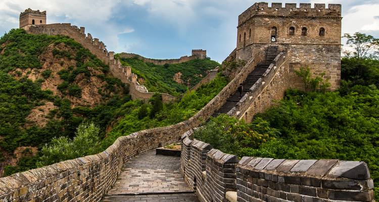 Stenen looppad en wachttorens van de Grote Muur van China die zich uitstrekt over groene heuvels
