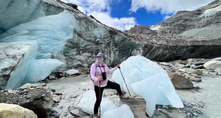 Femme randonneuse posant près de la glace glaciaire bleue avec des bâtons de trekking et un appareil photo.