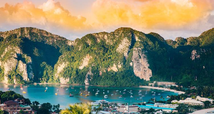 Vista aérea de la bahía turquesa rodeada de acantilados de piedra caliza y salpicada de botes en Phi Phi.