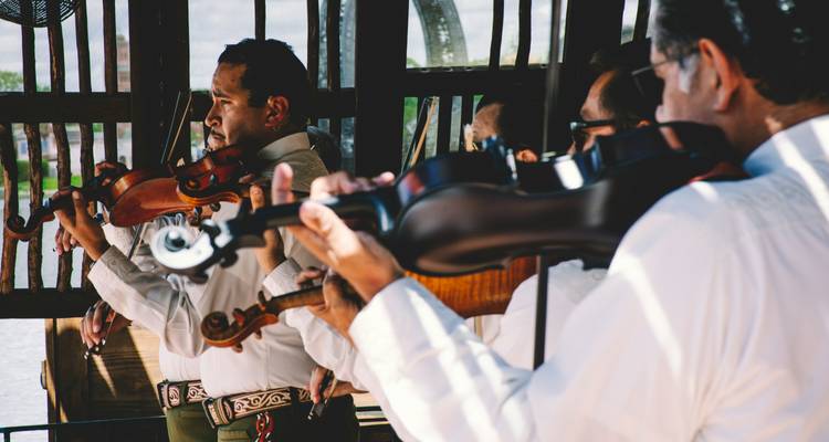 Mariachi-Musiker in traditioneller Kleidung spielen mit Violinen auf einer Open-Air-Bühne