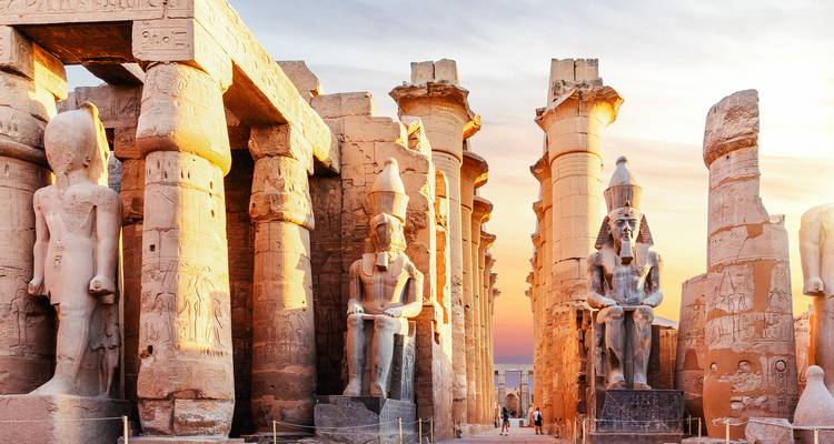 La lueur du coucher de soleil sur les statues colossales et les colonnes en forme de papyrus à l'intérieur du Temple de Louxor.