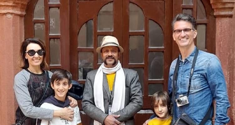 A family poses with their local guide in front of a traditional wooden doorway.