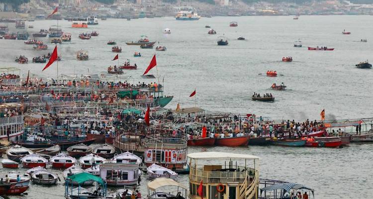 Überfüllte Ghats mit zahlreichen farbenfrohen Booten und Pilgern am Ganges-Fluss.
