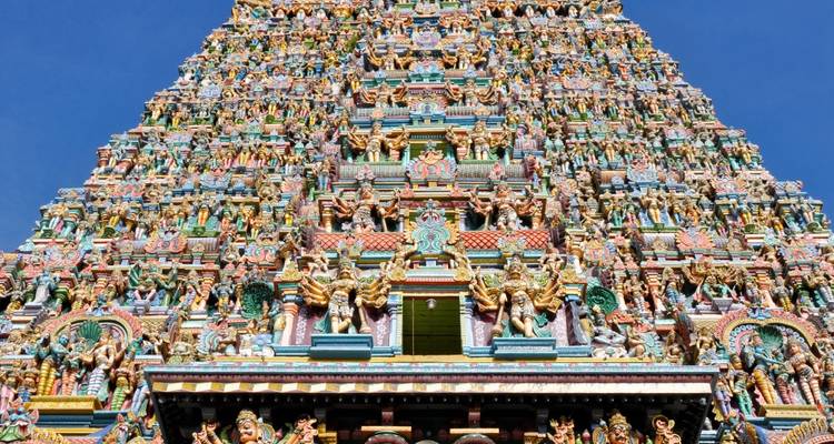 Uitstekende, rijkelijk versierde zuidelijke gopuram van de Meenakshi Amman-tempel tegen een helderblauwe hemel.