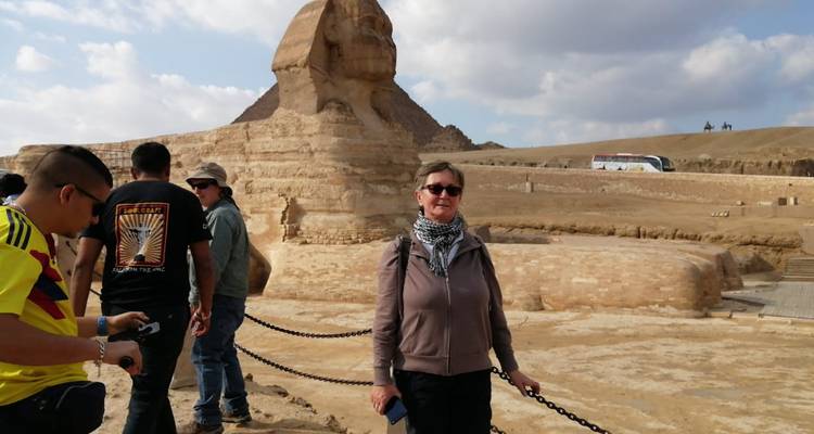 Bezoekers die voor de Grote Sphinx staan met zijn lichaam van kalksteen en piramides op de achtergrond op een heldere dag.