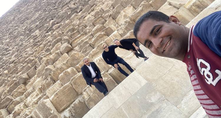 Selfie van gids en bezoekers die op de enorme kalksteenblokken van de Grote Piramide klimmen.