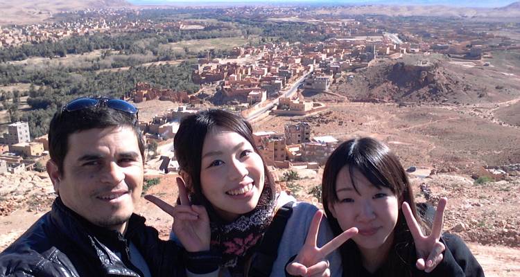 Selfie with friends overlooking an expansive desert village from viewpoint.