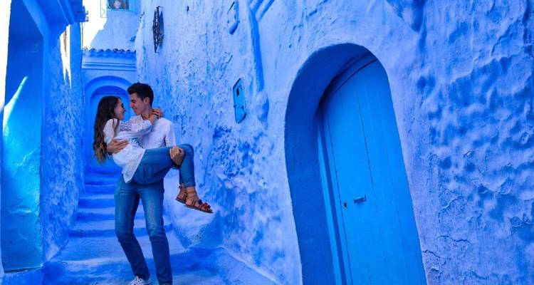 Romantic moment as man lifts woman in the vivid blue alleyways of Chefchaouen.