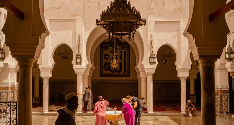 Visitors gather around a fountain inside an elegant arched courtyard with chandeliers.