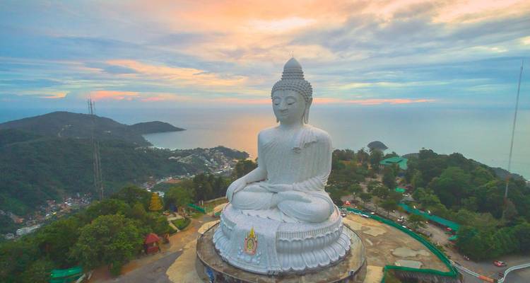 Vue aérienne au coucher du soleil de la statue du Grand Bouddha de Phuket surplombant la mer et les collines.