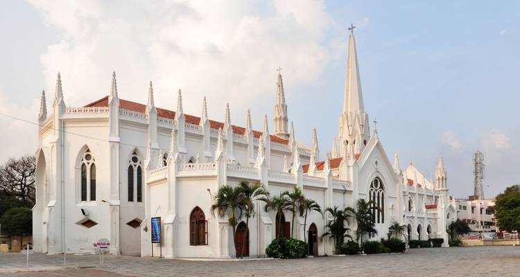 White neo-Gothic Santhome Cathedral with pointed spires and palm trees in Chennai.