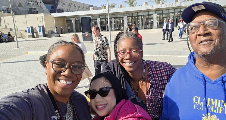 Een lachende groep maakt een selfie buiten de ingang van het Grand Egyptian Museum-complex.