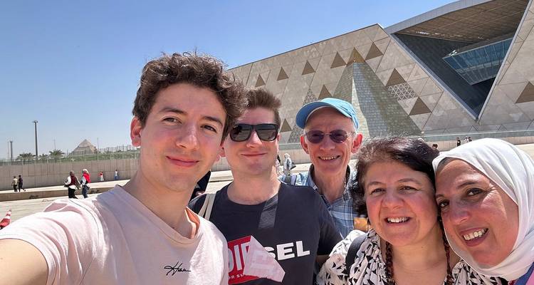 Vijf reizigers poseren voor een selfie voor de geometrische gevel van het Grand Egyptian Museum.