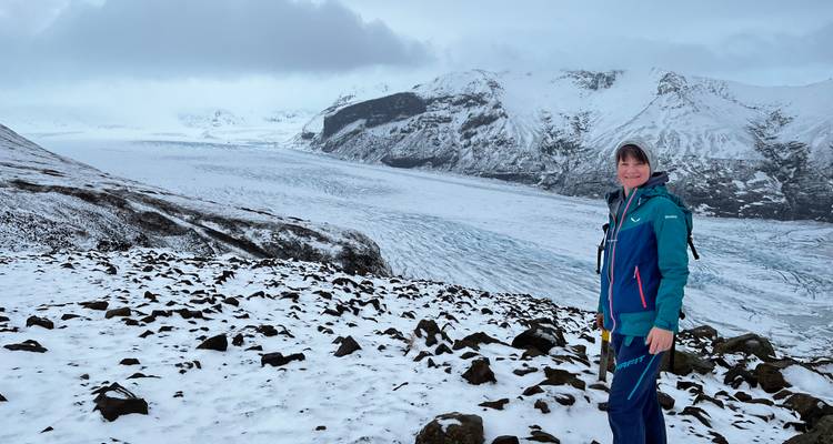 Wanderer, der auf einem verschneiten Grat steht und auf einen riesigen Gletscher und raue Gipfel blickt