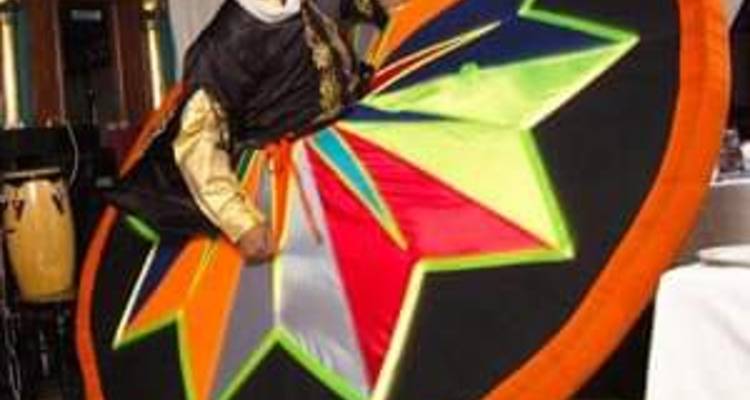 Danseur de tanoura coloré tournoyant avec une jupe multicolore sur scène.