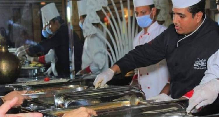 Des chefs en toque blanche servant la nourriture sous forme de buffet à bord d'un navire de croisière.