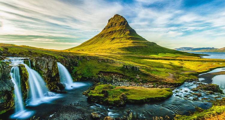 Iconische Kirkjufell-berg met twee watervallen die in gouden uur in een rustige rivier stromen.