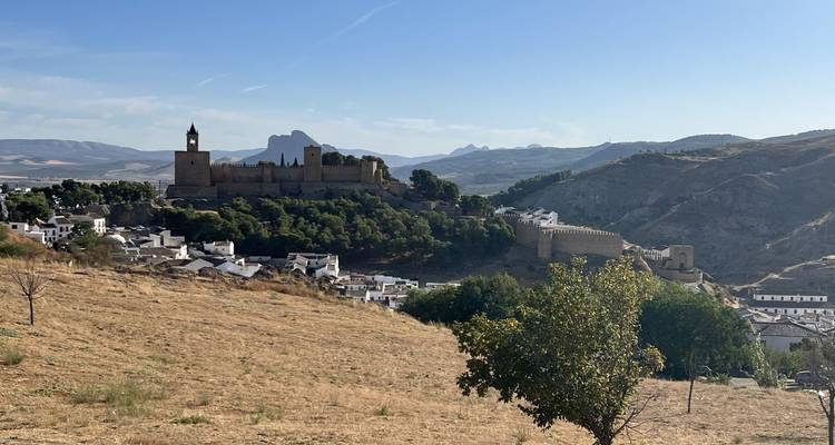 Eine entfernte Bergfestung und Kirche dominieren das Skyline der sonnenverwöhnten Landschaft von Antequera.