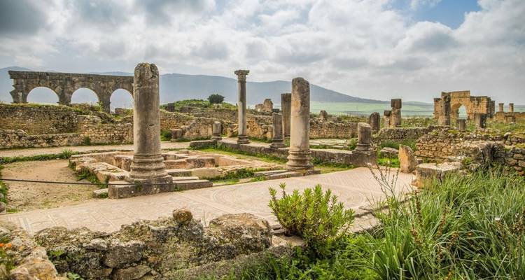 Les ruines romaines antiques et les sols en mosaïque situés parmi les collines verdoyantes sous des cieux partiellement nuageux