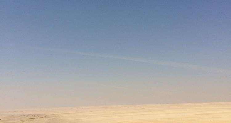 Vaste étendue désertique plate sous un ciel bleu brumeux sans points de repère distincts.