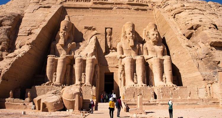 Toeristen lopen naar de indrukwekkende voorgevel van Abu Simbel onder een stralend blauwe hemel.